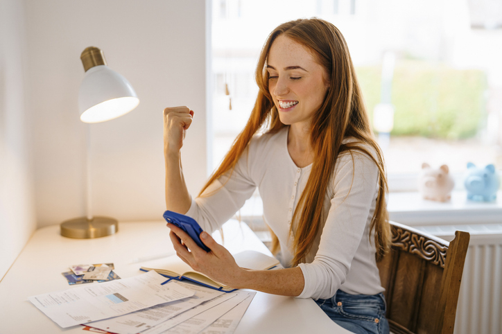 Young woman happily reviews her personal loan on her smartphone.