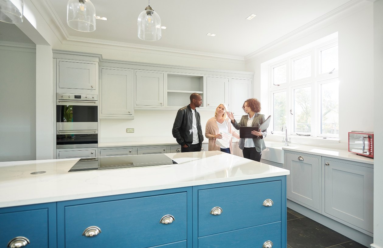 A realtor shows a kitchen to a couple.