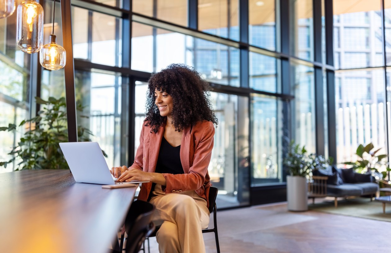 A woman smiles while on her laptop in an office