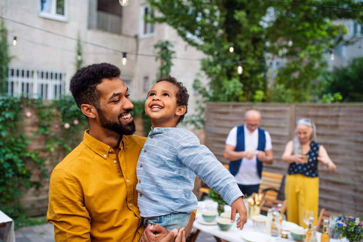 Happy father holds his young son in the air on their new backyard patio made possible by a home equity line of credit (HELOC).