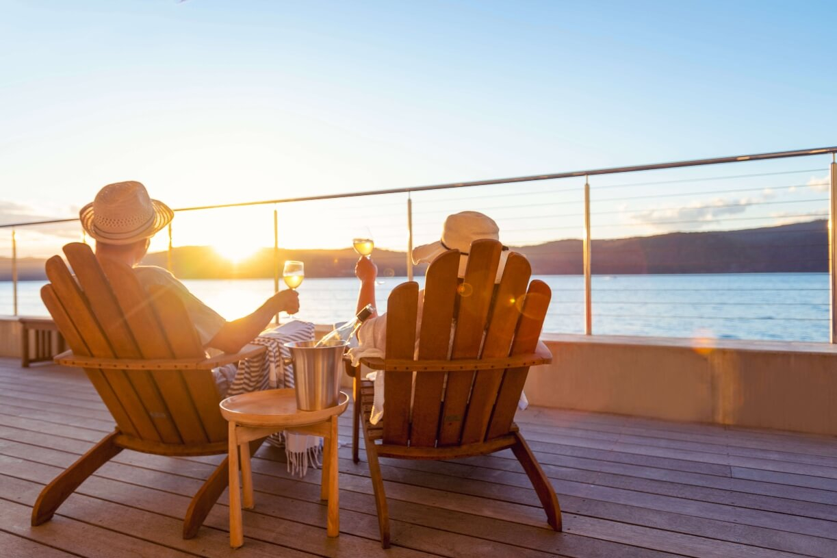 Young couple toast each other with champagne glasses on a cruise ship deck at sunset.