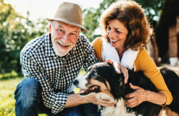 Happy couple plans for retirement in their garden with their dog. 