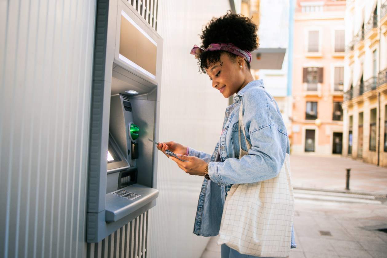 A woman uses an ATM outside