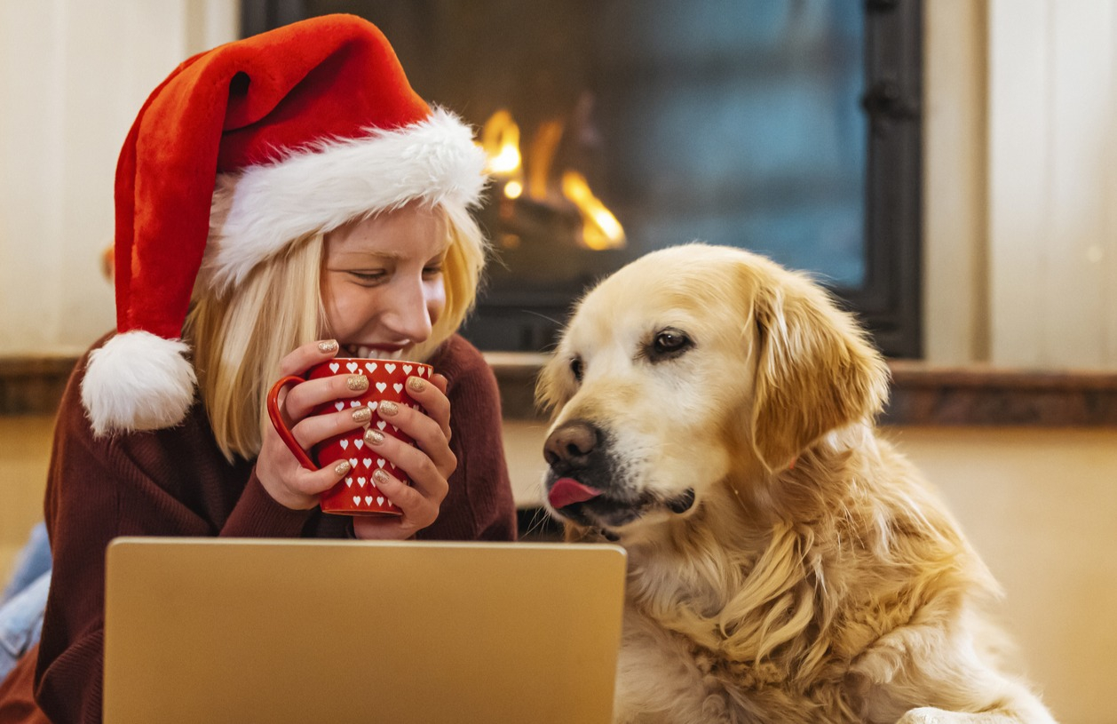 Woman does her holiday shopping on her laptop while wearing a Santa hat.