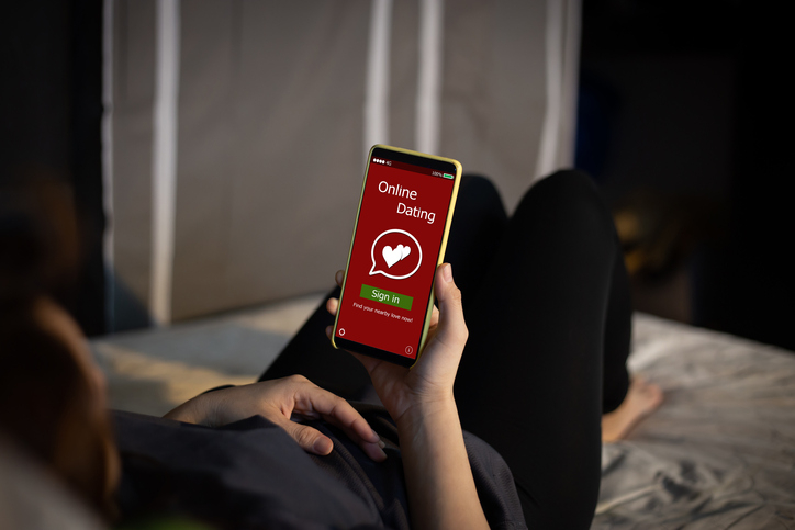 Single person with face hidden looks for love on an online dating app while relaxing at home.