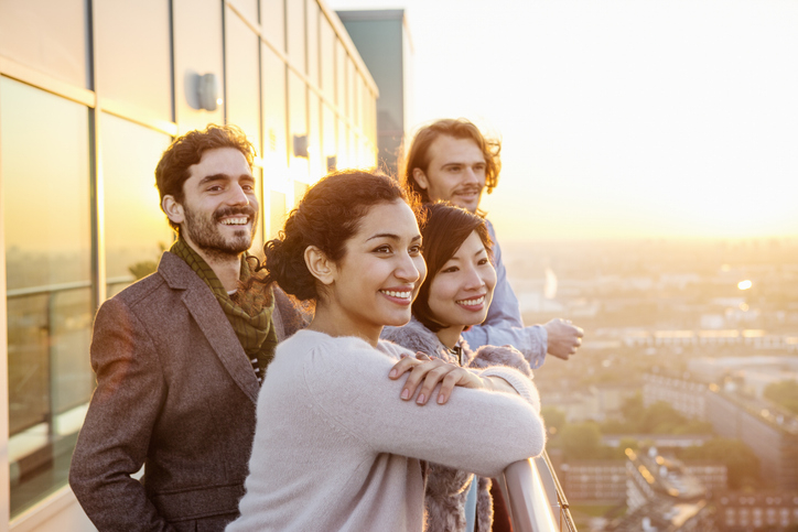 Group of 20-somethings look happily towards a sunset.