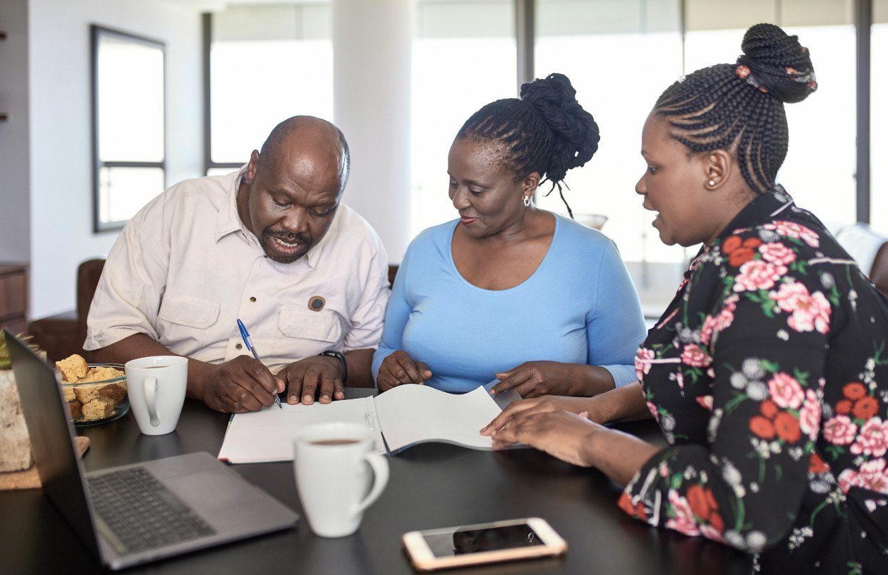 A woman sits at a table with an older couple going over financial documents