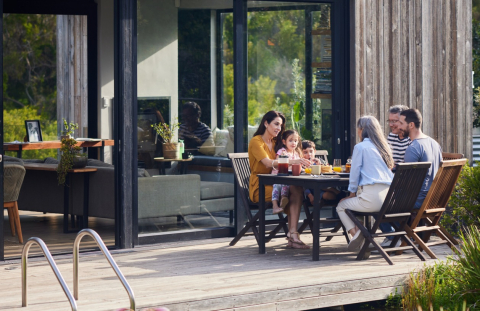 Multi-generational family eats dinner outside in their second home on lake.
