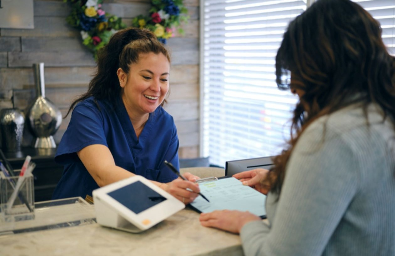 Woman pays healthcare expense with her credit card at doctor's office. 