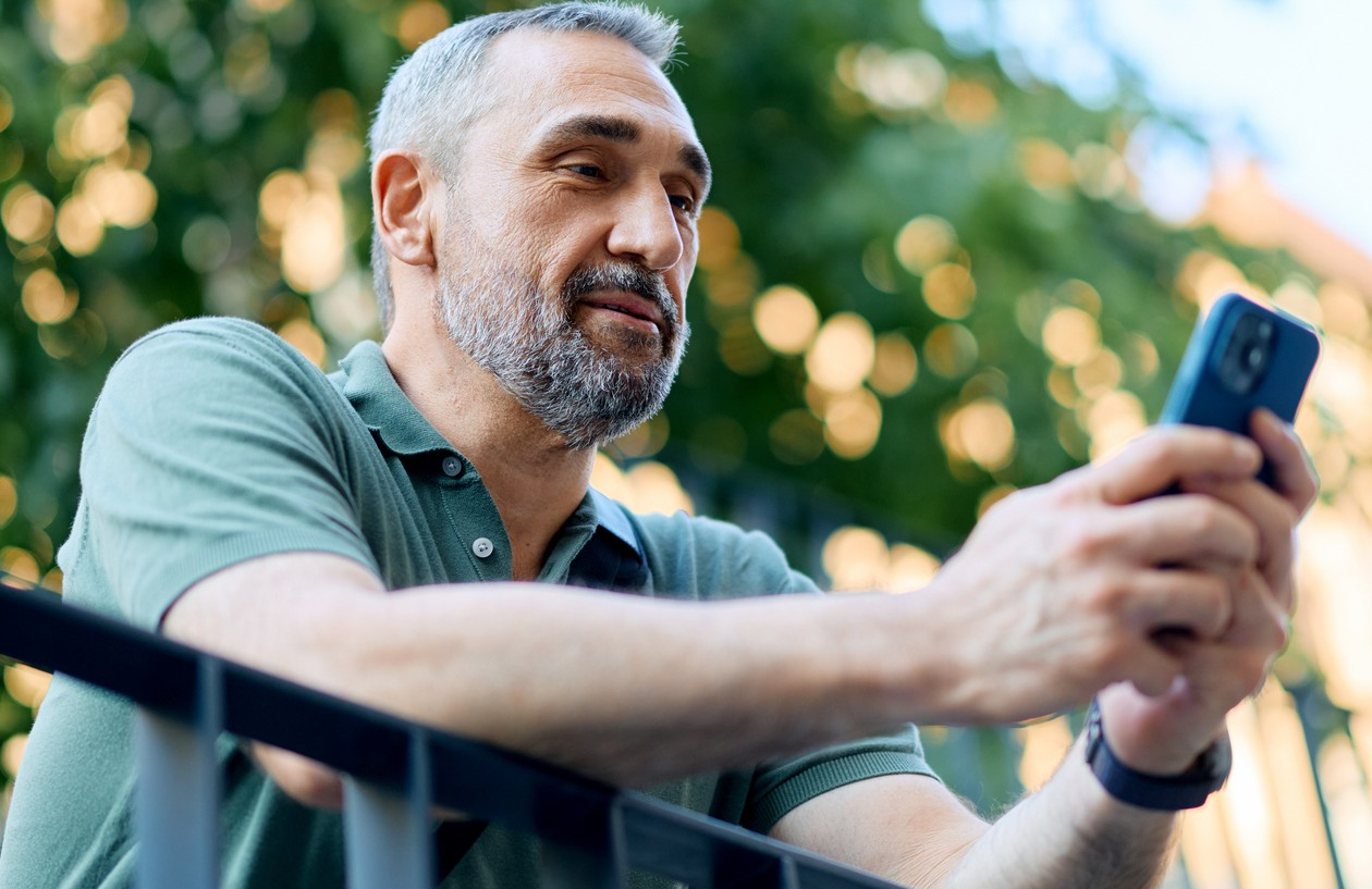 Middle-aged man reviews emails and texts for scams on his smartphone.