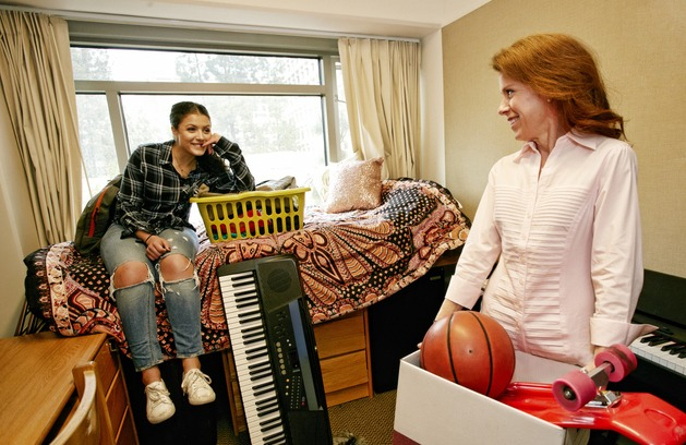 Mother happily unpacks her daughter at her college dorm, thanks to Suze Orman advice about student loan changes.