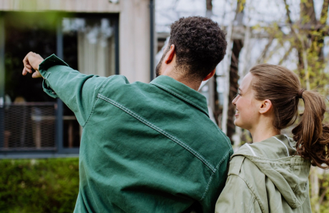 Happy married couple looks at the exterior of their house thinking about a home improvement project they could fund with home equity line of credit (HELOC).