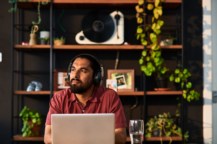 Bearded man considers opening a certificate (CD) account while researching on his laptop. 