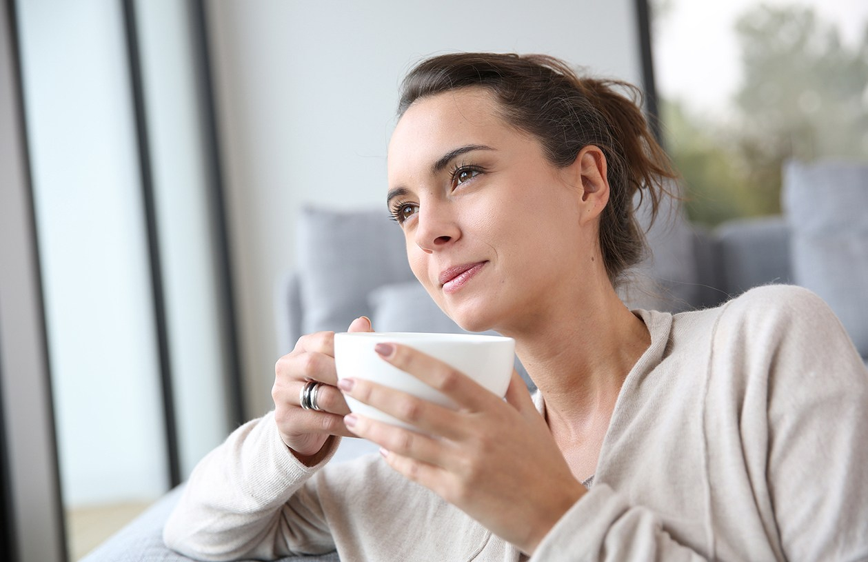 woman drinking tea while gazing out a window