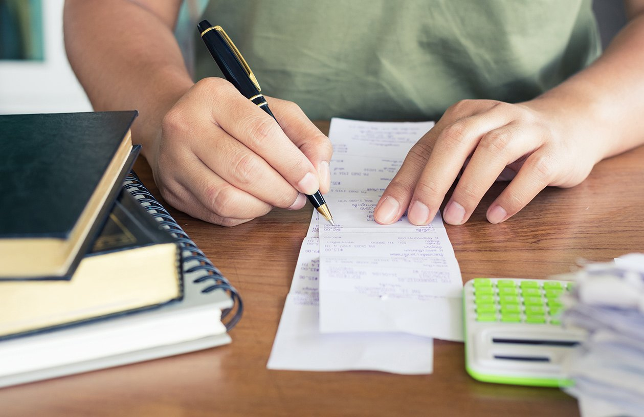 man with pen in hand going over his receipts
