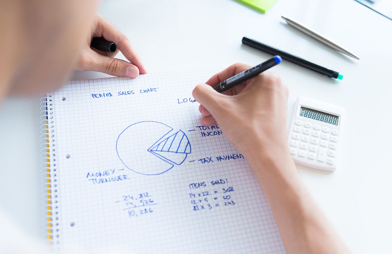 woman managing her budget in a spiral notebook with calculator next to her
