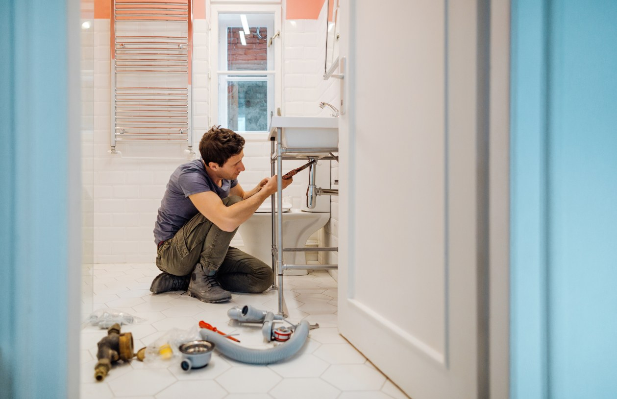 A plummer repairs a bathroom.
