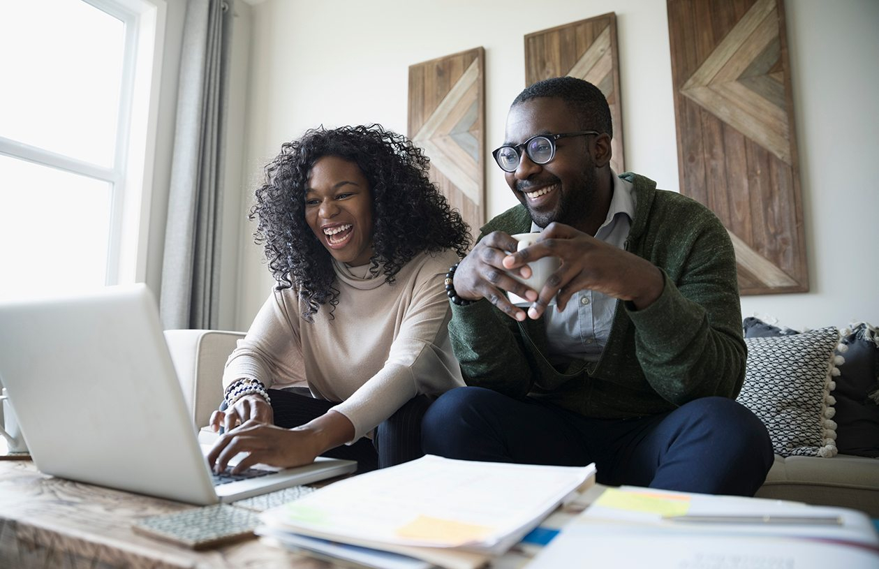 couple sitting in their living room looking at a laptop banking online