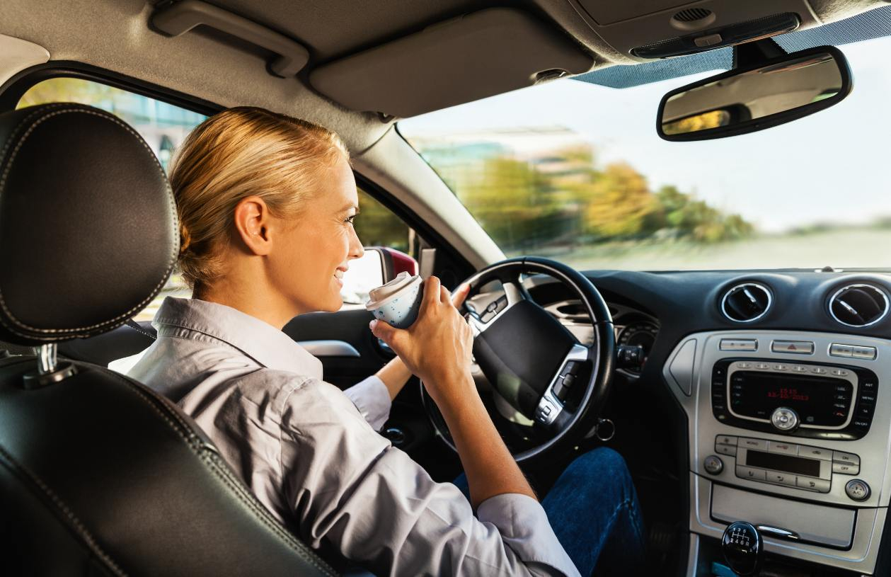 A woman drives in her car after she refinances her auto loan.