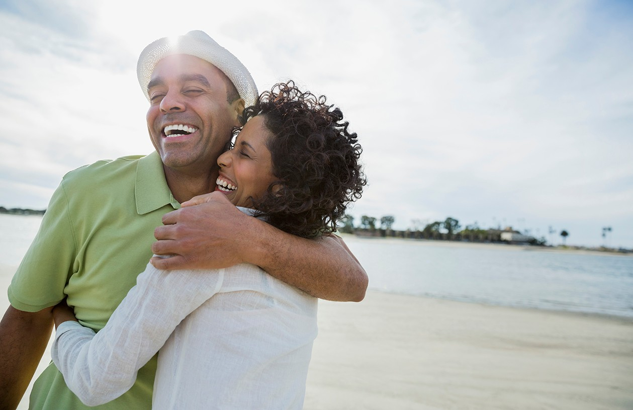 smiling couple hugging on the beach excited about retirement